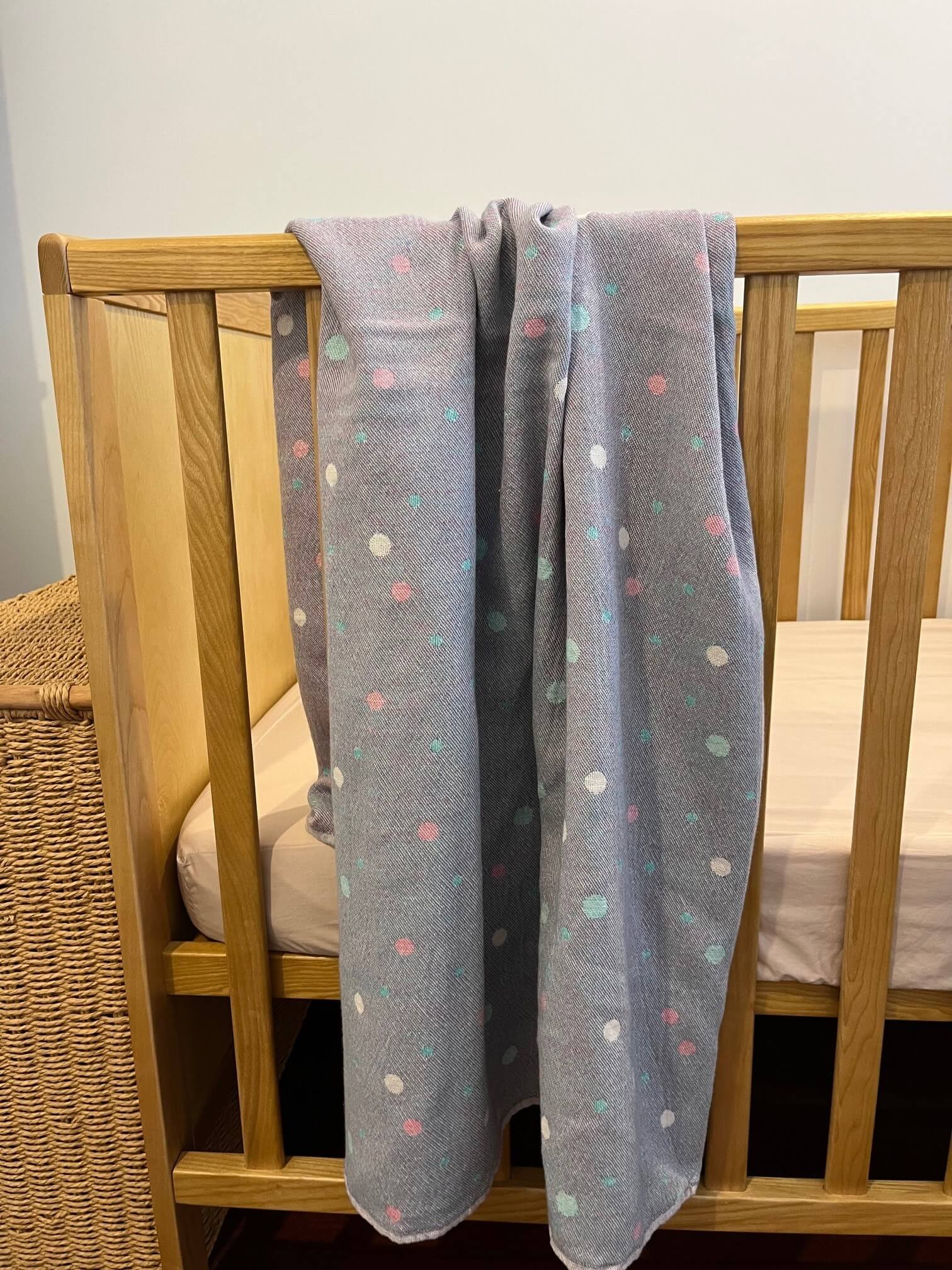 double sided baby blanket with dots shown on a cot
